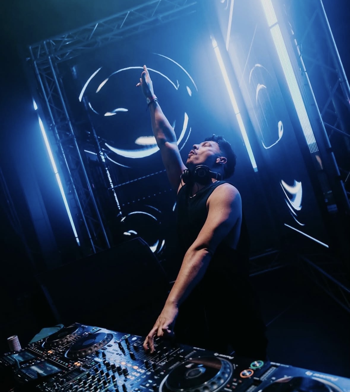 Low-angle shot of Joey iLLah reaching up under blue stage lights