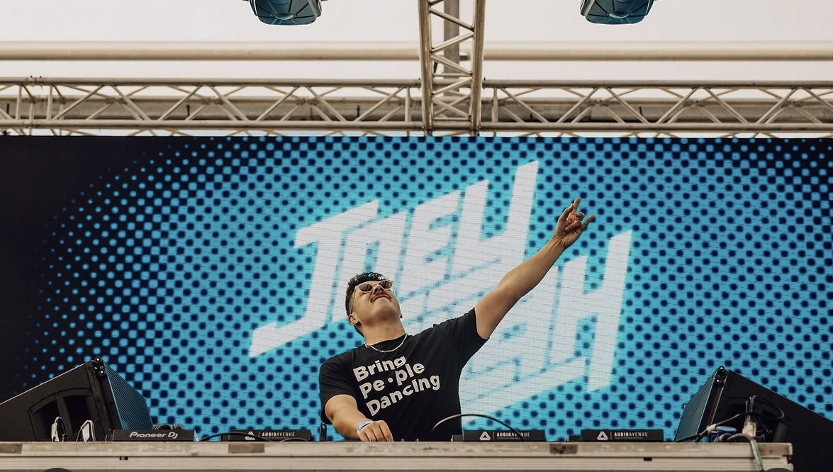 Joey iLLah pointing skyward with his JOEY iLLah name on a huge blue LED screen