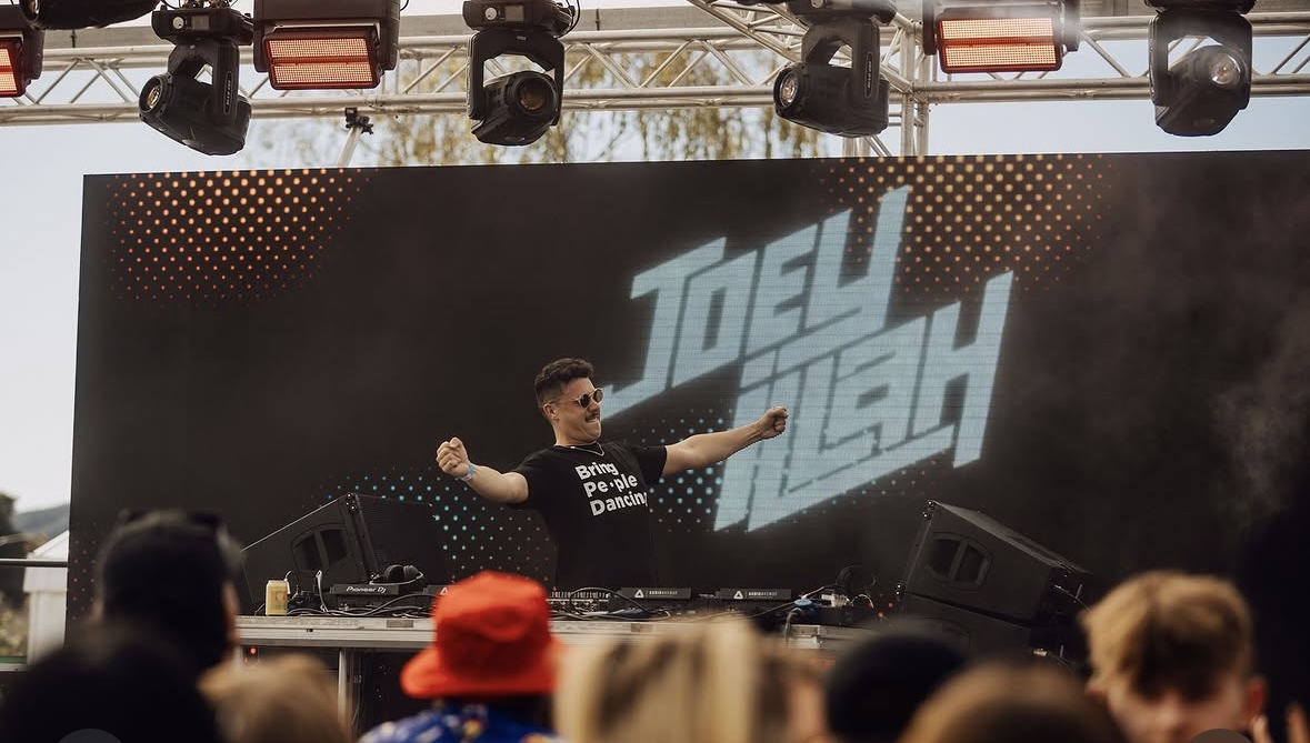 Joey iLLah arms wide with his name on screen and crowd in the foreground
