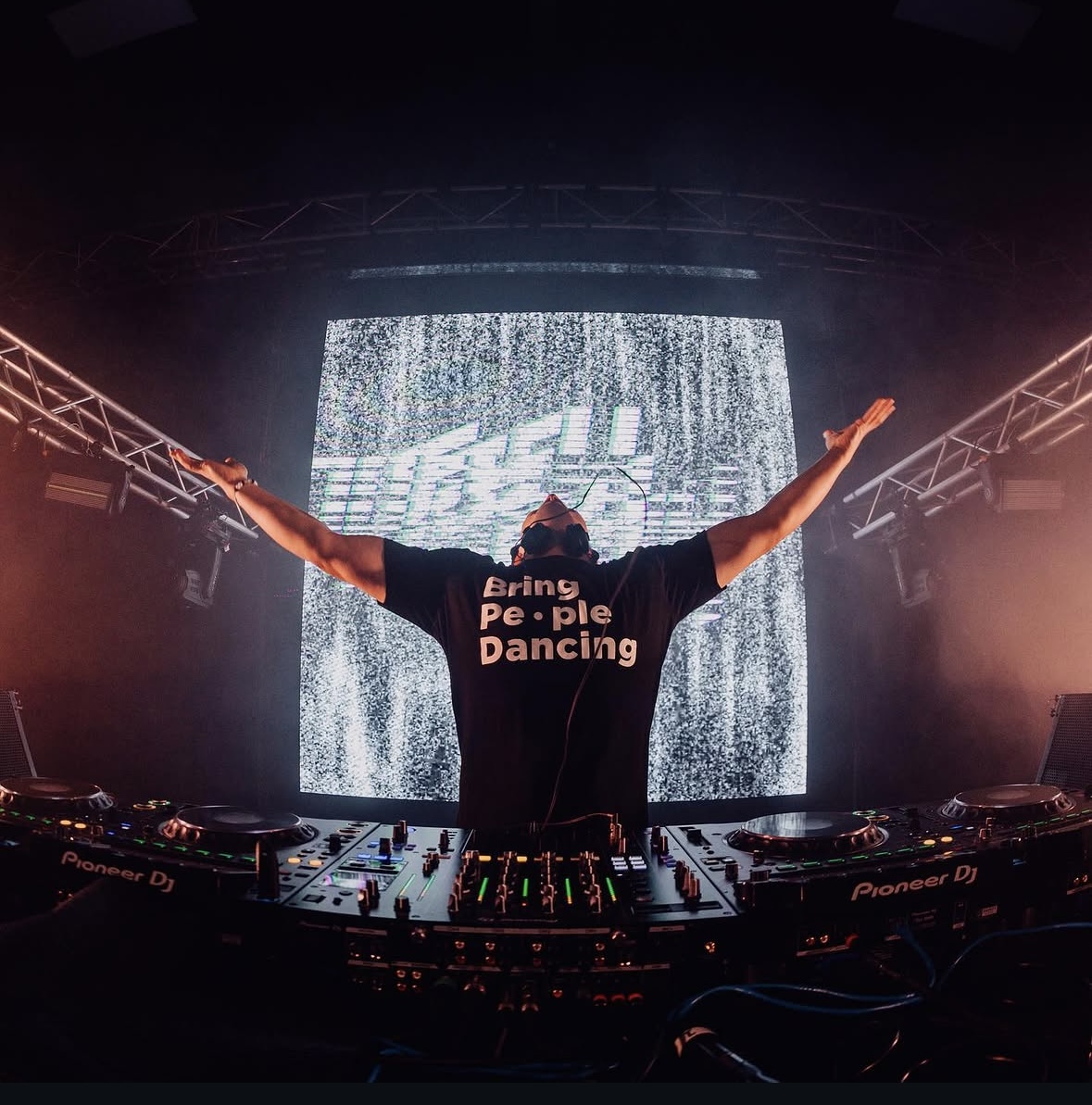 Joey iLLah performing with arms raised, wearing his 'Bring People Dancing' shirt